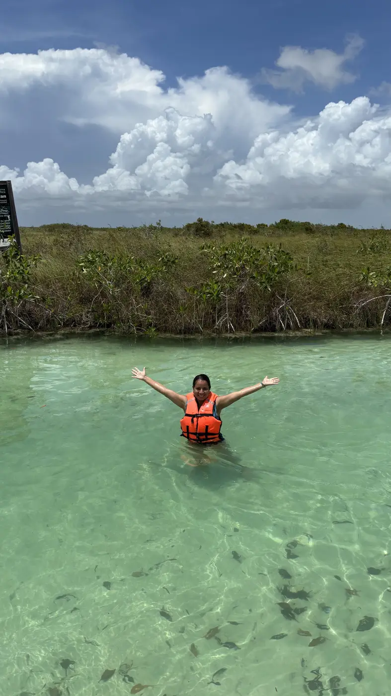 Person with open arms in the turquoise waters of Sian Ka'an, a symbol of a new chapter
