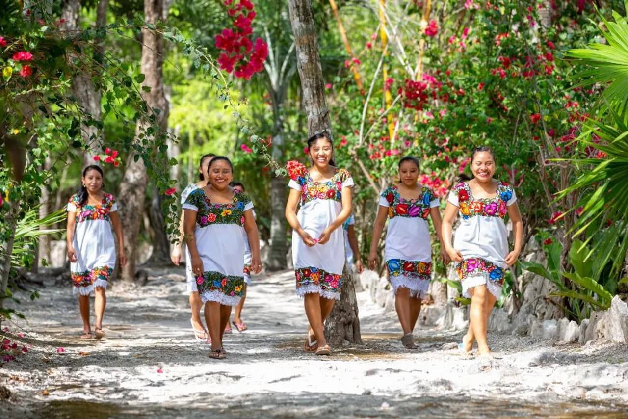 Maya women in traditional embroidered dresses on a path in the Maya Jungle